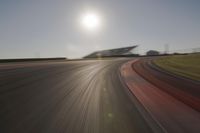 blurred shot of race track with car on one side and sun in the other side