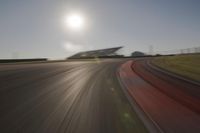 blurred shot of race track with car on one side and sun in the other side