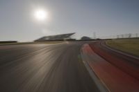 blurred shot of race track with car on one side and sun in the other side