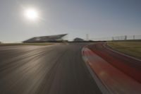 blurred shot of race track with car on one side and sun in the other side