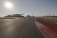 blurred shot of race track with car on one side and sun in the other side