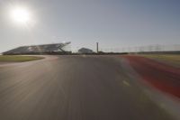 blurred shot of race track with car on one side and sun in the other side