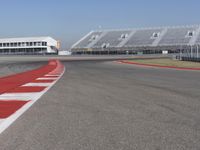 an empty track at a motorsports club with some red and white stripeing on it