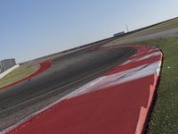 an empty track at a motorsports club with some red and white stripeing on it