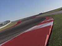 an empty track at a motorsports club with some red and white stripeing on it