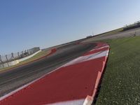 an empty track at a motorsports club with some red and white stripeing on it