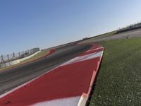 an empty track at a motorsports club with some red and white stripeing on it