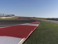 an empty track at a motorsports club with some red and white stripeing on it