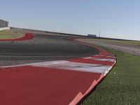 an empty track at a motorsports club with some red and white stripeing on it