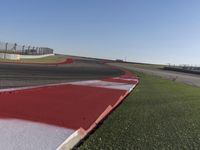 an empty track at a motorsports club with some red and white stripeing on it