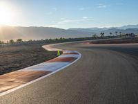 a photo of a dirt race track with sun setting in the distance of the track