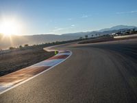 a photo of a dirt race track with sun setting in the distance of the track