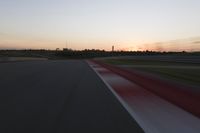 Race Track at Dawn: An Automobile Speeds Along the Line