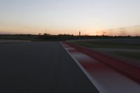 Race Track at Dawn: An Automobile Speeds Along the Line