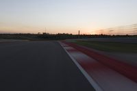 Race Track at Dawn: An Automobile Speeds Along the Line