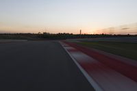 Race Track at Dawn: An Automobile Speeds Along the Line