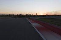 Race Track at Dawn: An Automobile Speeds Along the Line