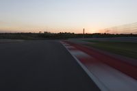 Race Track at Dawn: An Automobile Speeds Along the Line