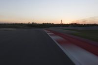 Race Track at Dawn: An Automobile Speeds Along the Line