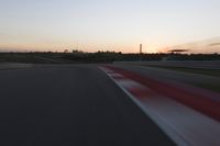 Race Track at Dawn: An Automobile Speeds Along the Line