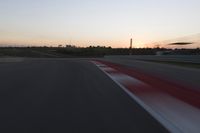 Race Track at Dawn: An Automobile Speeds Along the Line