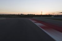 Race Track at Dawn: An Automobile Speeds Along the Line