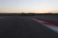 Race Track at Dawn: An Automobile Speeds Along the Line