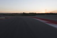 Race Track at Dawn: An Automobile Speeds Along the Line