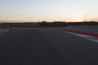 Race Track at Dawn: An Automobile Speeds Along the Line