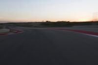 Race Track at Dawn: An Automobile Speeds Along the Line