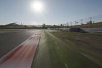 a view of the sun from a vehicle in motion on a race track in a blurry, light filled, open area