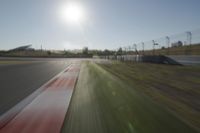 a view of the sun from a vehicle in motion on a race track in a blurry, light filled, open area