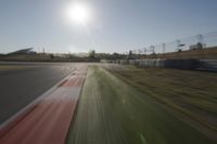 a view of the sun from a vehicle in motion on a race track in a blurry, light filled, open area