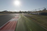 a view of the sun from a vehicle in motion on a race track in a blurry, light filled, open area