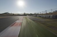 a view of the sun from a vehicle in motion on a race track in a blurry, light filled, open area