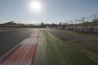 a view of the sun from a vehicle in motion on a race track in a blurry, light filled, open area