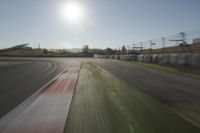 a view of the sun from a vehicle in motion on a race track in a blurry, light filled, open area