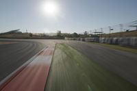 a view of the sun from a vehicle in motion on a race track in a blurry, light filled, open area