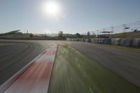 a view of the sun from a vehicle in motion on a race track in a blurry, light filled, open area