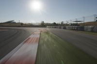 a view of the sun from a vehicle in motion on a race track in a blurry, light filled, open area