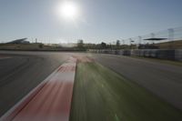 a view of the sun from a vehicle in motion on a race track in a blurry, light filled, open area