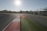 a view of the sun from a vehicle in motion on a race track in a blurry, light filled, open area