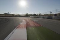 a view of the sun from a vehicle in motion on a race track in a blurry, light filled, open area