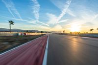 a photo of a dirt race track with sun setting in the distance of the track