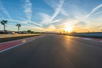 a photo of a dirt race track with sun setting in the distance of the track