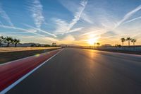 a photo of a dirt race track with sun setting in the distance of the track