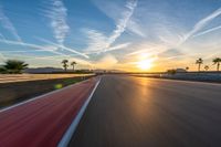 a photo of a dirt race track with sun setting in the distance of the track