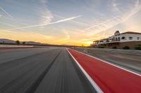 a photo of a dirt race track with sun setting in the distance of the track