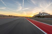 a photo of a dirt race track with sun setting in the distance of the track