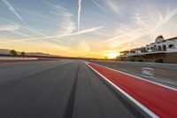 a photo of a dirt race track with sun setting in the distance of the track